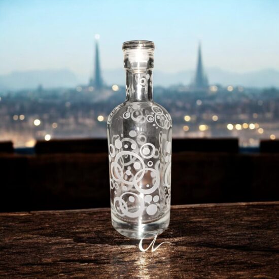 Bouteille en verre gravée. La bouteille est vide et transparente. Des cercles évoquant des bulles sont gravées dessus